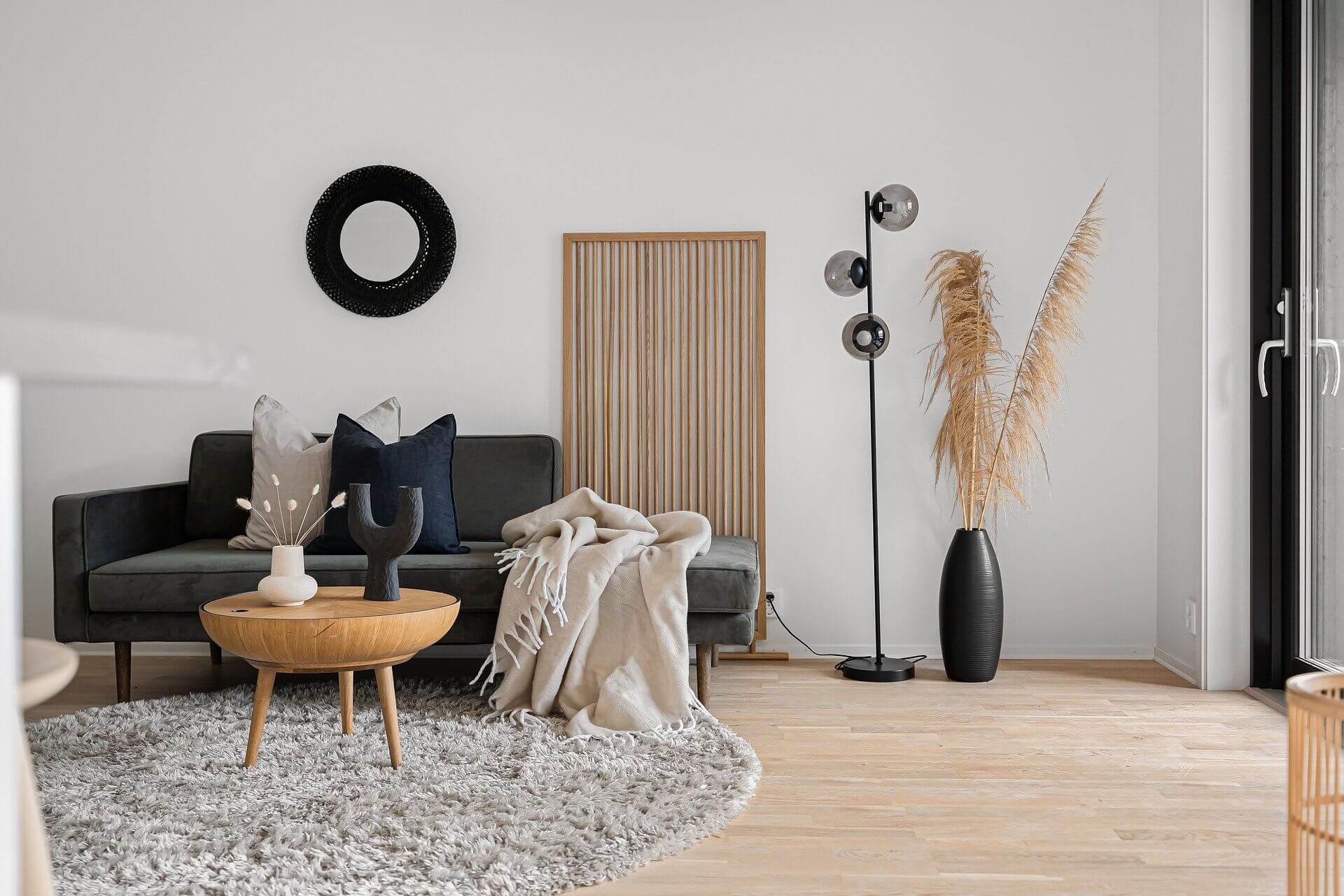 Modernes Wohnzimmer im Organic-Style mit runden Holztischen, grauem Sofa, Pampasgras und minimalistischer Dekoration