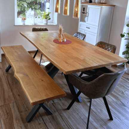 Essgruppe mit tisch und bank aus eiche, beide mit naturbelassener baumkante, auf schwarzem gestell.