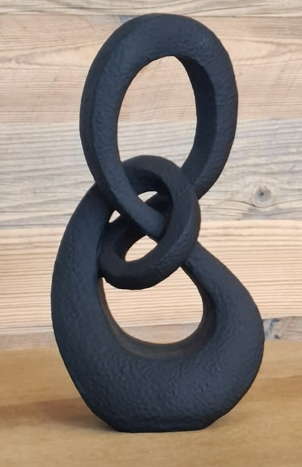 Schwarze designskulptur mit organischer form auf holztisch
