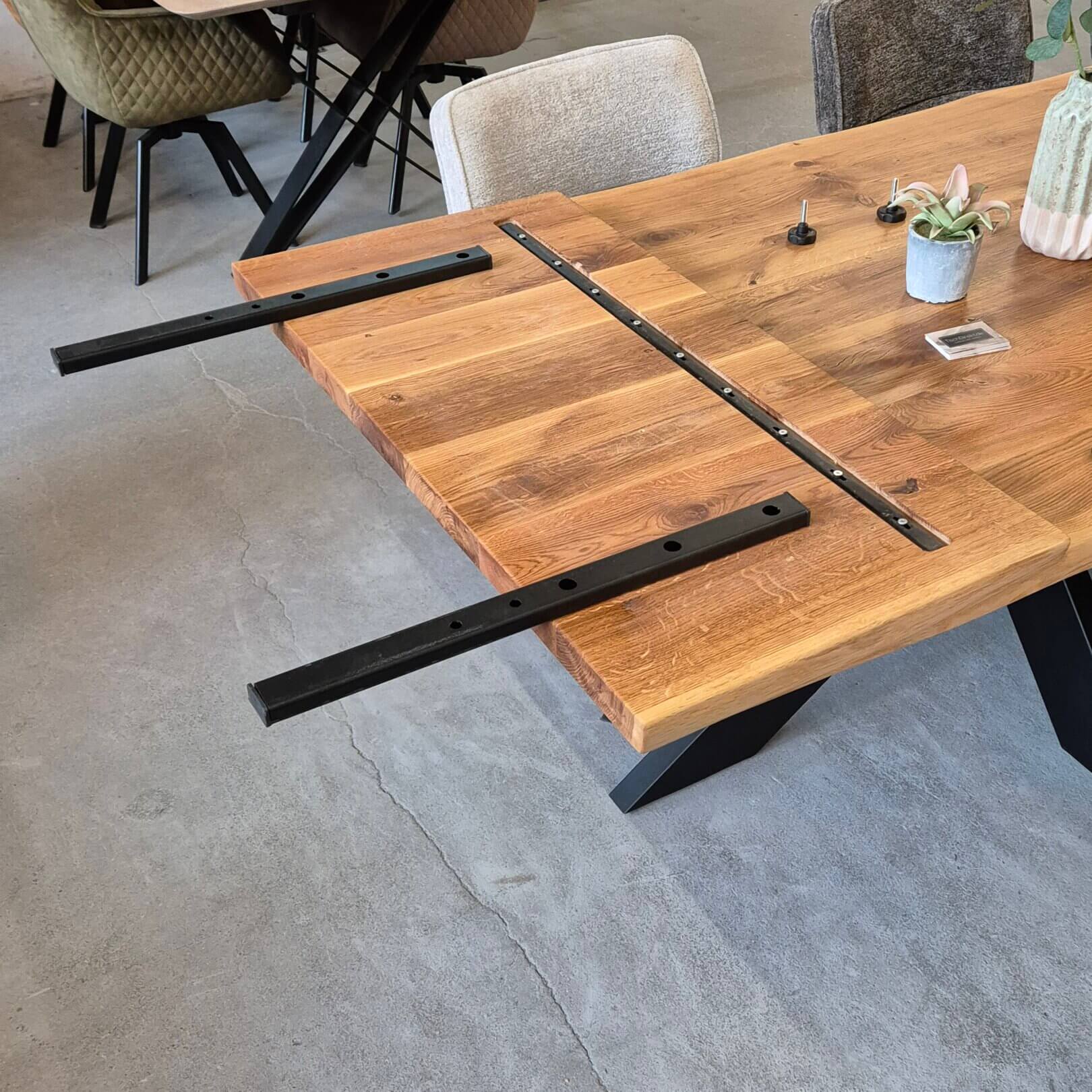 Ansteckplatte aus geöltem eichenholz mit eingelassener stahlgradleiste und stabilem schwarzen stahl-schienensystem zur befestigung an massivholztisch.