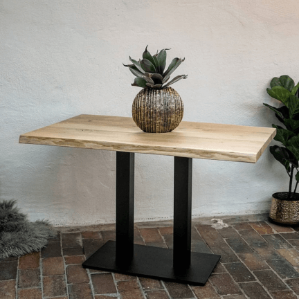 Tisch aus gastroplatte mit naturbelassener baumkante auf schwarzem metallgestell